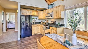 A modern kitchen with wooden cabinets, stainless steel appliances, and a dining area with a wooden table and chairs. - California Cabin w/ Lake Access: 28 Mi to Yosemite (Groveland)