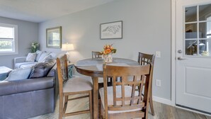 Un coin repas avec une table ronde, des chaises en bois et un vase rempli de fleurs.