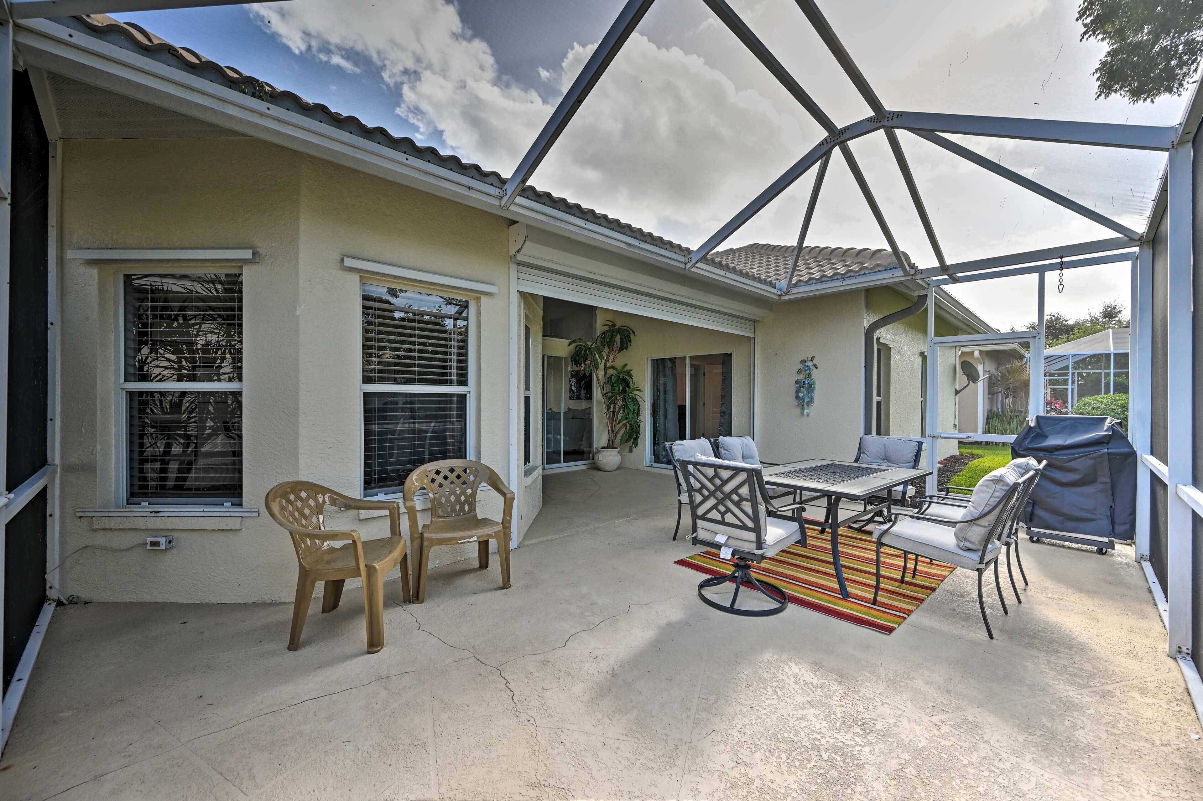 A covered patio with a table and chairs, a grill, and a view of the house.