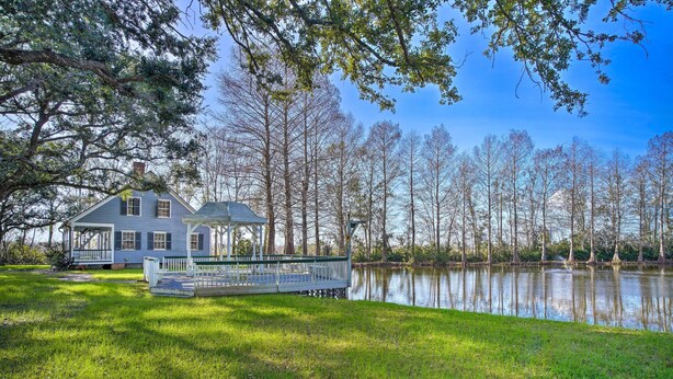 A house with a dock extending into a lake, surrounded by trees. - Idyllic Houma Vacation Rental on Shared Pond! (Houma)