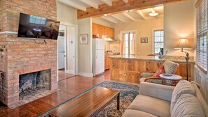 A cozy living room with a fireplace, a television mounted on the brick wall, a sofa, and a coffee table. - Idyllic Houma Vacation Rental on Shared Pond! (Houma)