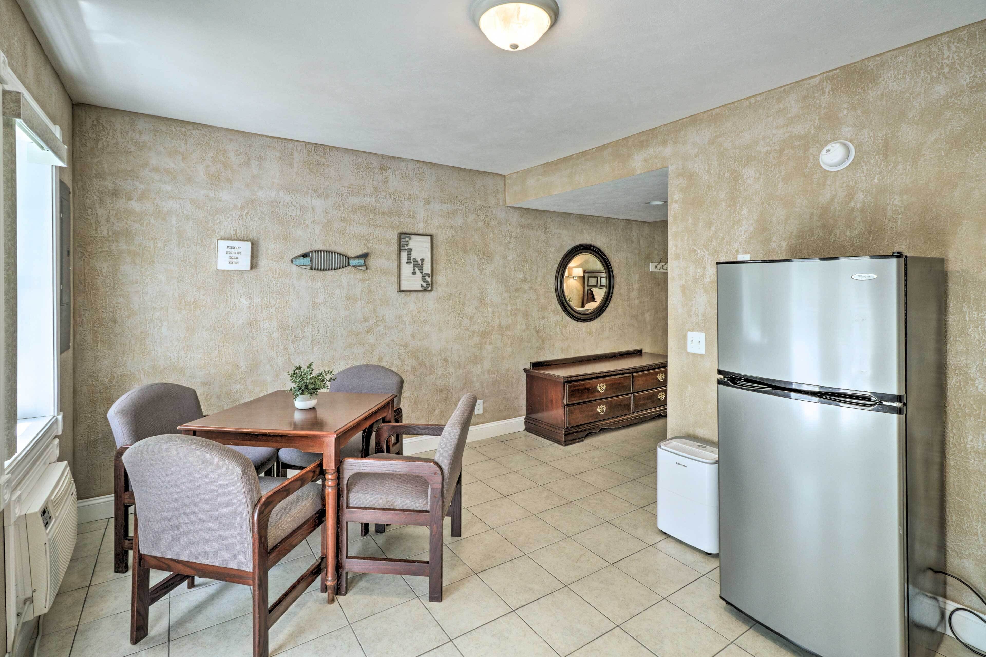 A kitchen with a dining table, chairs, a refrigerator, and a small white appliance.