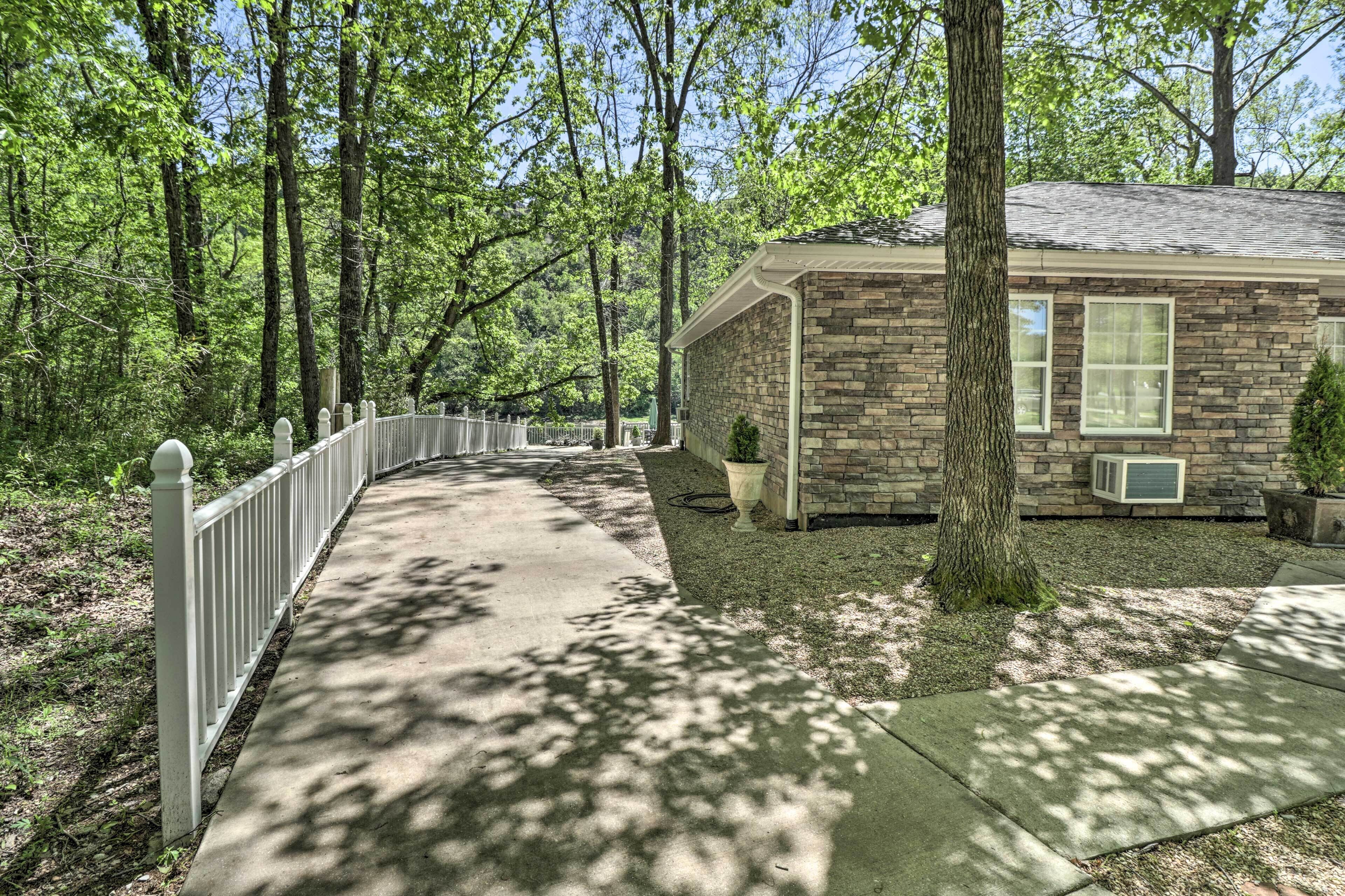 A house with a stone facade, a front porch, and a pathway leading to the entrance.