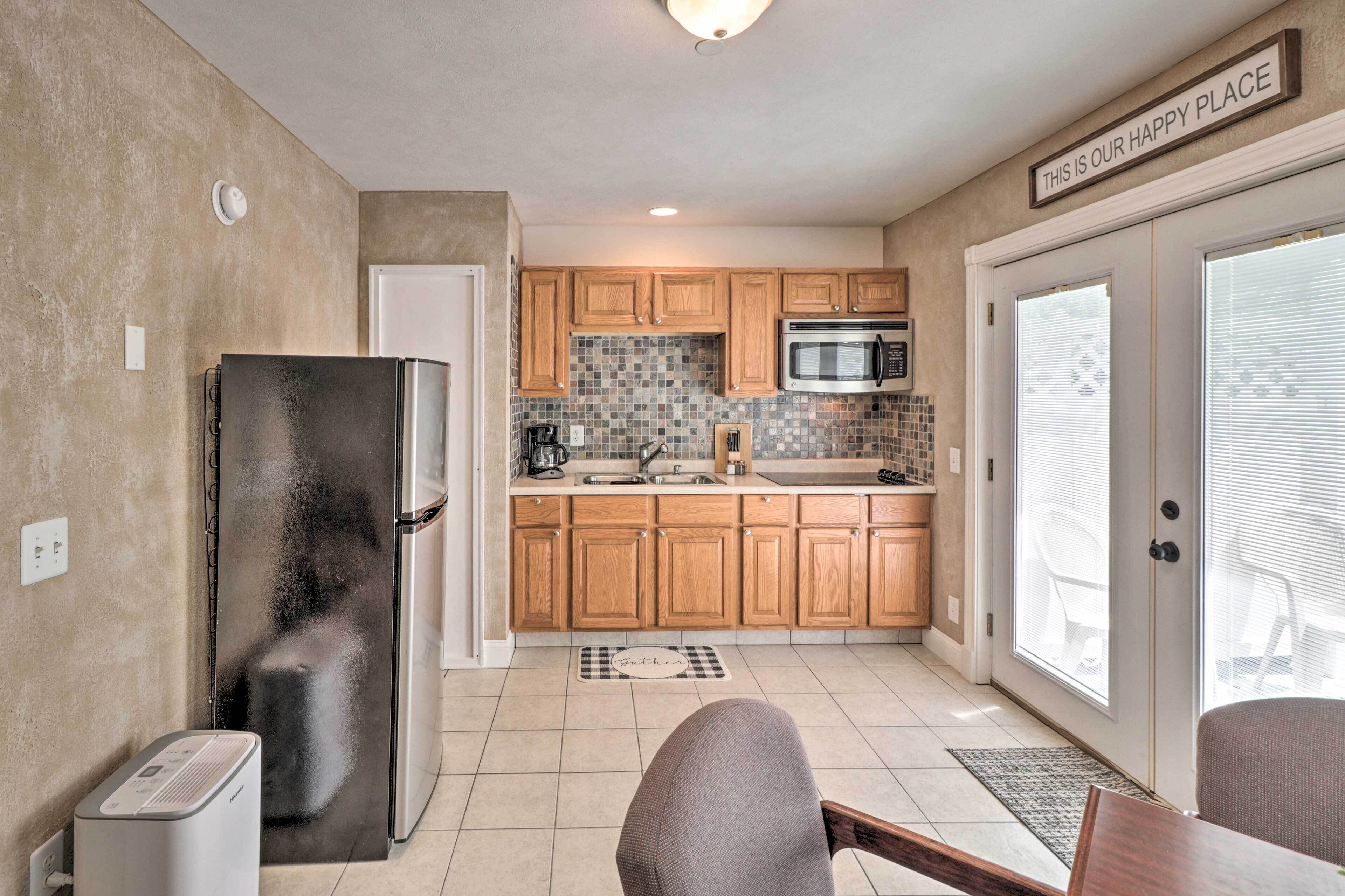 A compact kitchen with wooden cabinets, a stainless steel refrigerator, and a microwave.