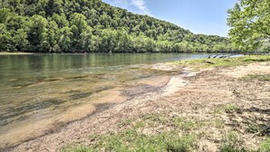 Orilla de río con una ladera boscosa al fondo.
