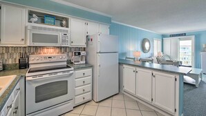 A kitchen with white cabinets, a stove, microwave, and refrigerator. - Beachfront Condo w/ Boardwalk & Pool Access! (Atlantic Beach)