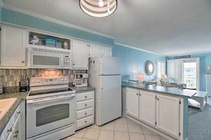 A kitchen with white cabinets, a stove, microwave, and refrigerator. - Beachfront Condo w/ Boardwalk & Pool Access! (Atlantic Beach)