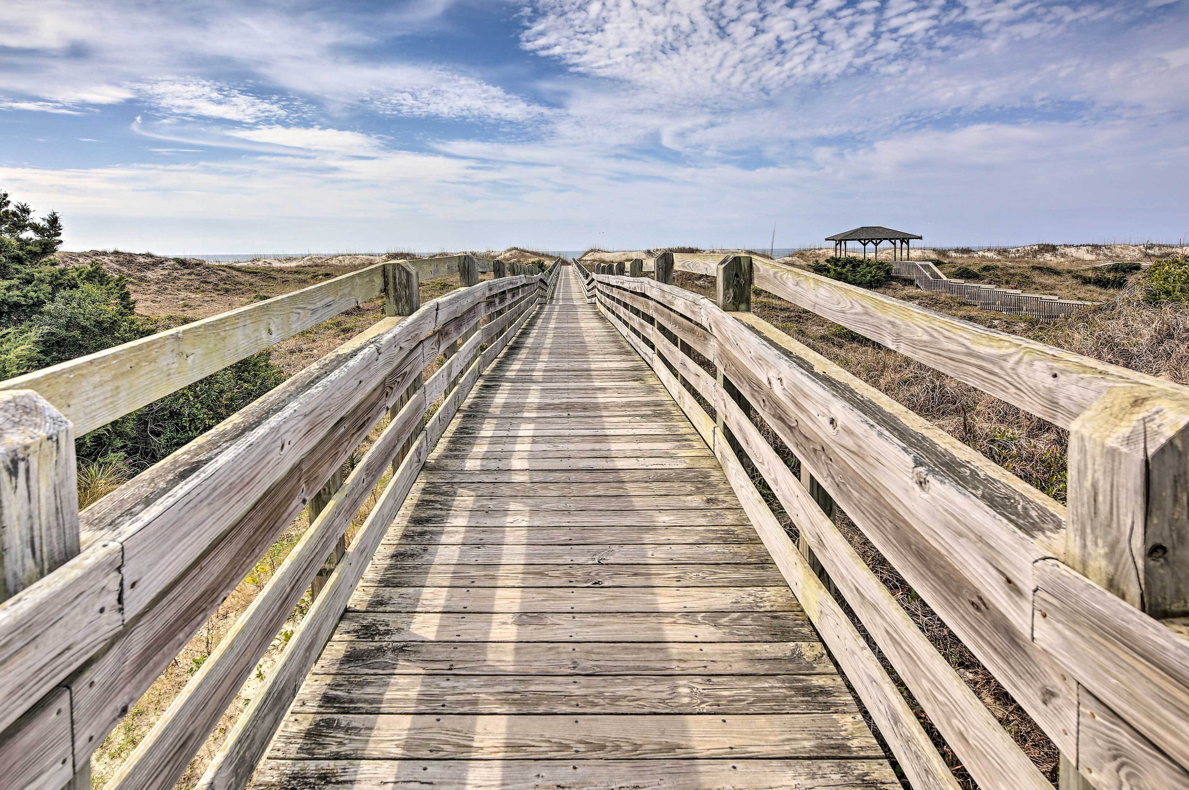 A wooden boardwalk leading to a gazebo on a beach.