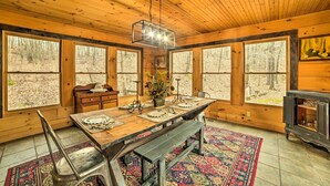 A wooden cabin interior with a dining table, benches, and large windows. - Quiet Cabin Retreat on 30 Acres Near Kentucky Lake (New Concord)