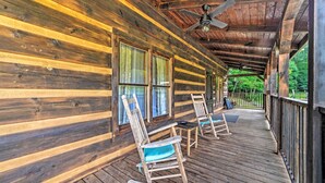 A wooden cabin with a porch, rocking chairs, and a ceiling fan. - Quiet Cabin Retreat on 30 Acres Near Kentucky Lake (New Concord)