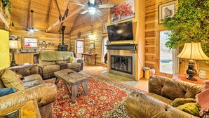 A cozy log cabin interior with leather sofas, a fireplace, a television, and wooden walls. - Quiet Cabin Retreat on 30 Acres Near Kentucky Lake (New Concord)
