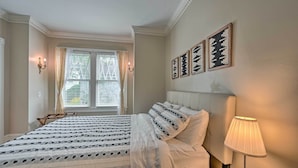 Un lit bien fait, avec une couvre-lit à motifs, une lampe de chevet et des œuvres d’art accrochées au mur.