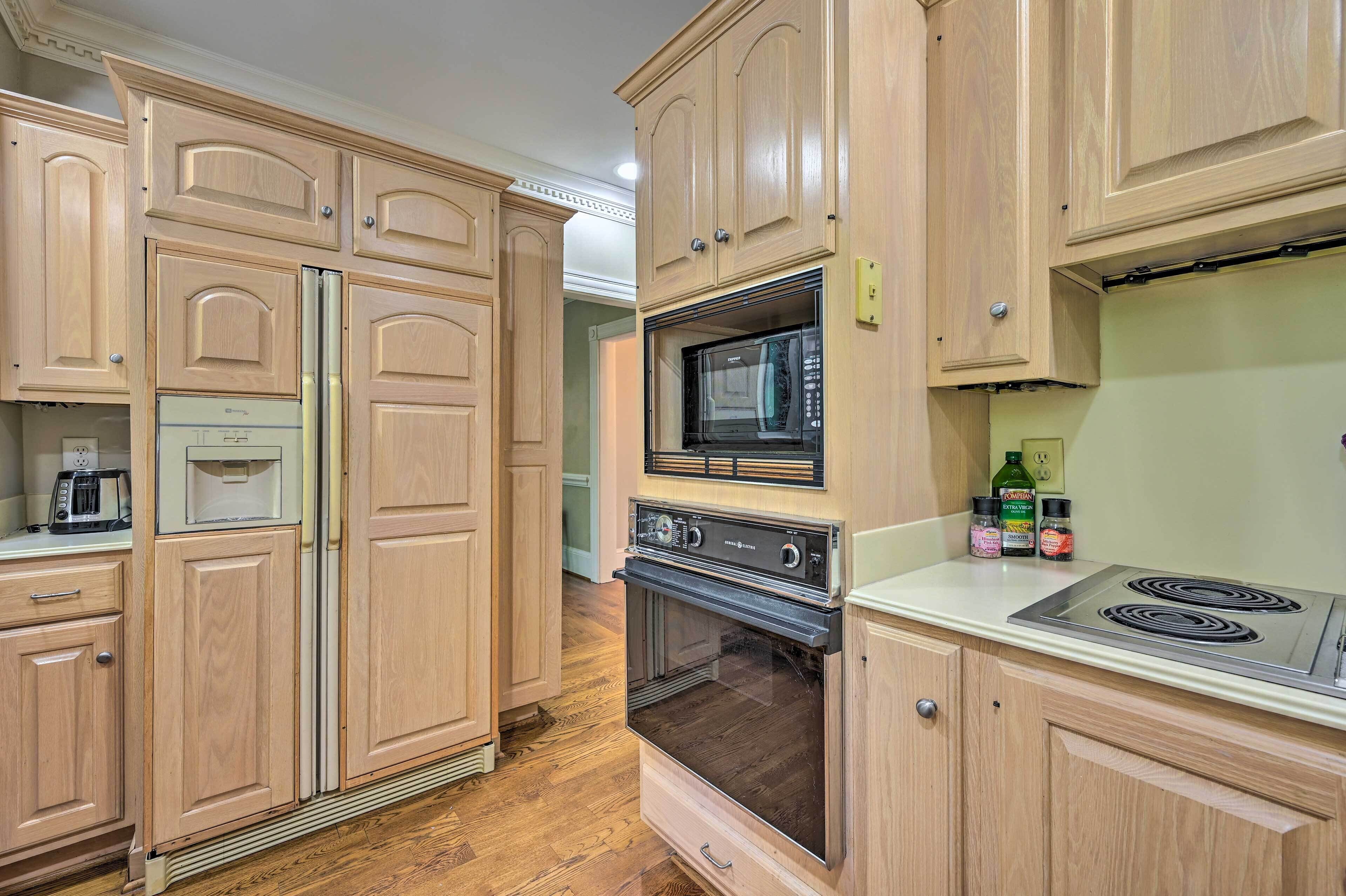 Une cuisine avec des meubles de rangement en bois, un réfrigérateur, un four à micro-ondes, un four et une plaque de cuisson.