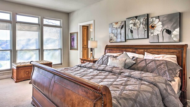 A bedroom with a large bed, a wooden headboard, a nightstand, a lamp, and three wall-mounted flower paintings.