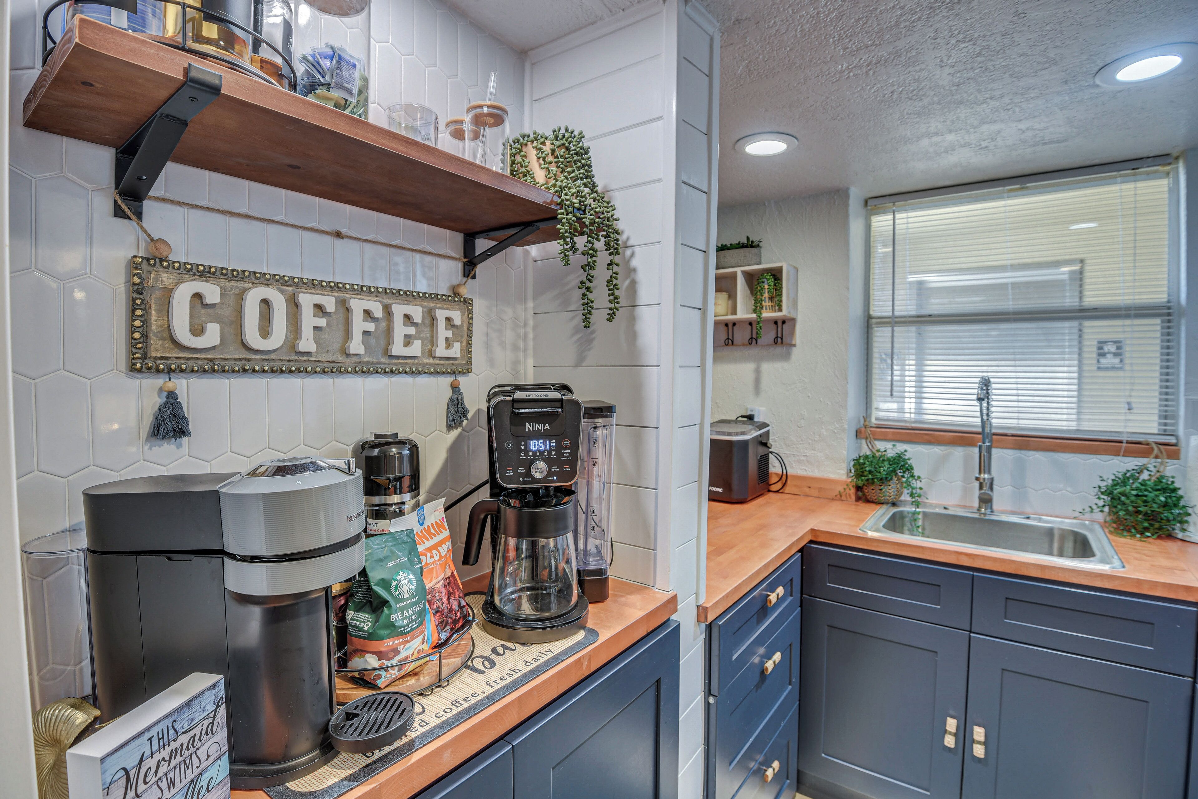 Eine Küche mit einer Kaffeestation, einer Kaffeemaschine, einem Mixer und einem Schild mit Kaffeemotiv.