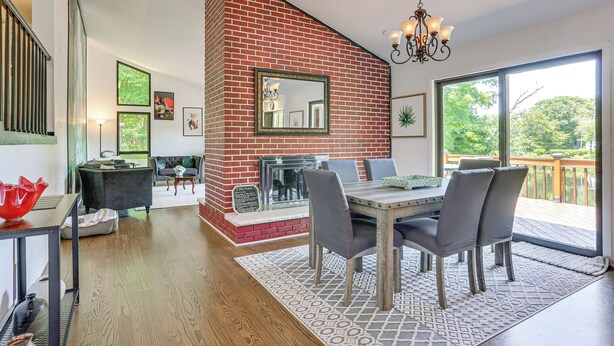 A dining area with a brick fireplace, a chandelier, and a view of the outdoors. - Pet-friendly Vacation Rental w/ Lake Access (Newton)