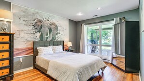 A bedroom with a large bed, a dresser, a painting of elephants, and a window with curtains. - Pet-friendly Vacation Rental w/ Lake Access (Newton)