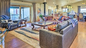 A spacious living room with a large sofa, a coffee table, and a view to the outside. - Beulah Home w/ Wraparound Porch & Mtn Views (Beulah)