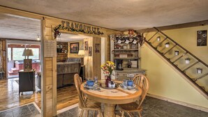 A cozy dining area with a wooden table and chairs, a coffee station, and a staircase with potted plants. - Supreme Family Getaway in the White Mountains! (Rumney)