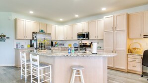A modern kitchen with a central island, white bar stools, and light wood cabinetry. - 2 Mi to Beach: Ocean View Oasis w/ Resort Access! (Ocean View)