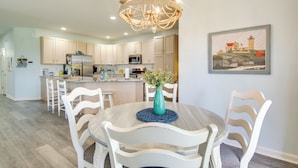 A modern kitchen with white cabinets, a central island, and a chandelier. - 2 Mi to Beach: Ocean View Oasis w/ Resort Access! (Ocean View)