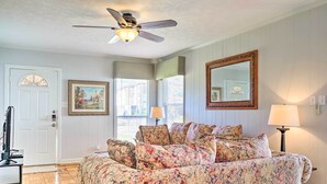 A room with a floral-patterned sofa, a ceiling fan, a large mirror, and a door with a window. - Pet-friendly Home w/ Patio - 3 Mi to Houston Zoo! (Houston)