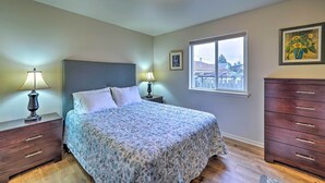 A bedroom with a bed, two bedside tables with lamps, a dresser, a window with a view, and a framed picture on the wall. - Anacortes Condo - Walk to Town, Marina, + Bay! (Anacortes)