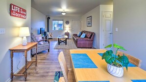 A cozy living room with a wooden coffee table, a leather sofa, and a dining table with blue placemats. - Anacortes Condo - Walk to Town, Marina, + Bay! (Anacortes)
