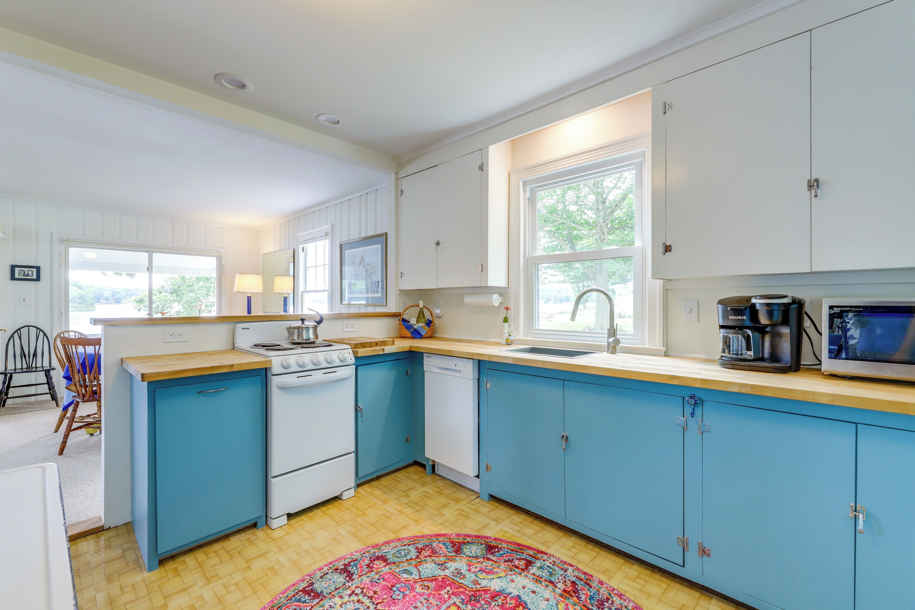 A kitchen with blue cabinets, a stove, a dishwasher, and a coffee maker.