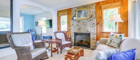 Un salón acogedor con muebles de mimbre, una chimenea y vistas al exterior.