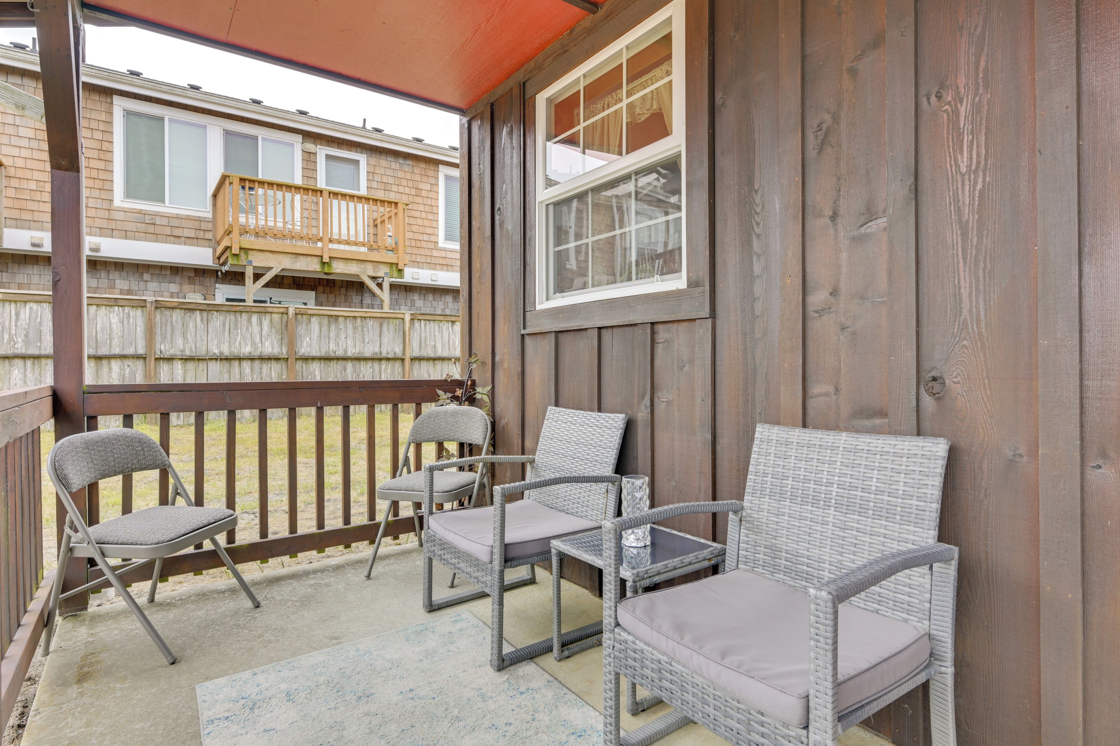 Un patio couvert, aménagé avec des meubles en osier, d’où l’on peut admirer un immeuble d’habitation.