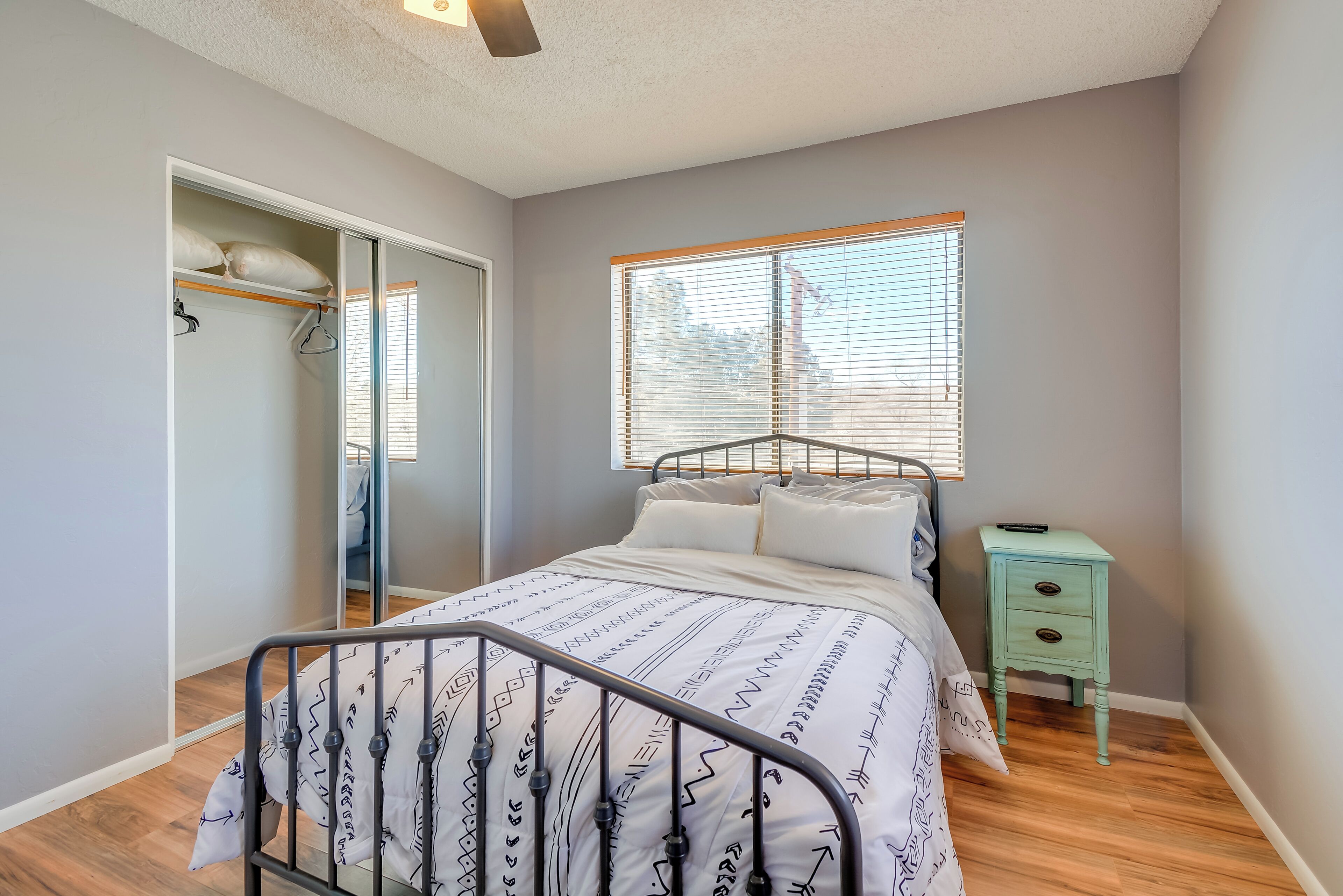 A bedroom with a bed, a bedside table, a wardrobe, and a window.