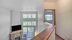 Ein großzügiger Wohnraum mit Kamin, großen Fenstern und einer Holztreppe.