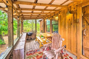A wooden porch with a table and benches, a grill, and large windows. - Mountian View Retreat < 2 Mi to White River! (Mountain View)