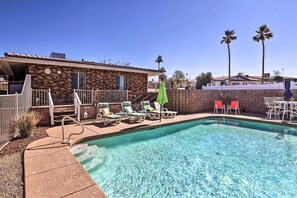 A swimming pool with lounge chairs and a brick building in the background. - Private Pool & Patio: Lake Havasu Home (Lake Havasu City)