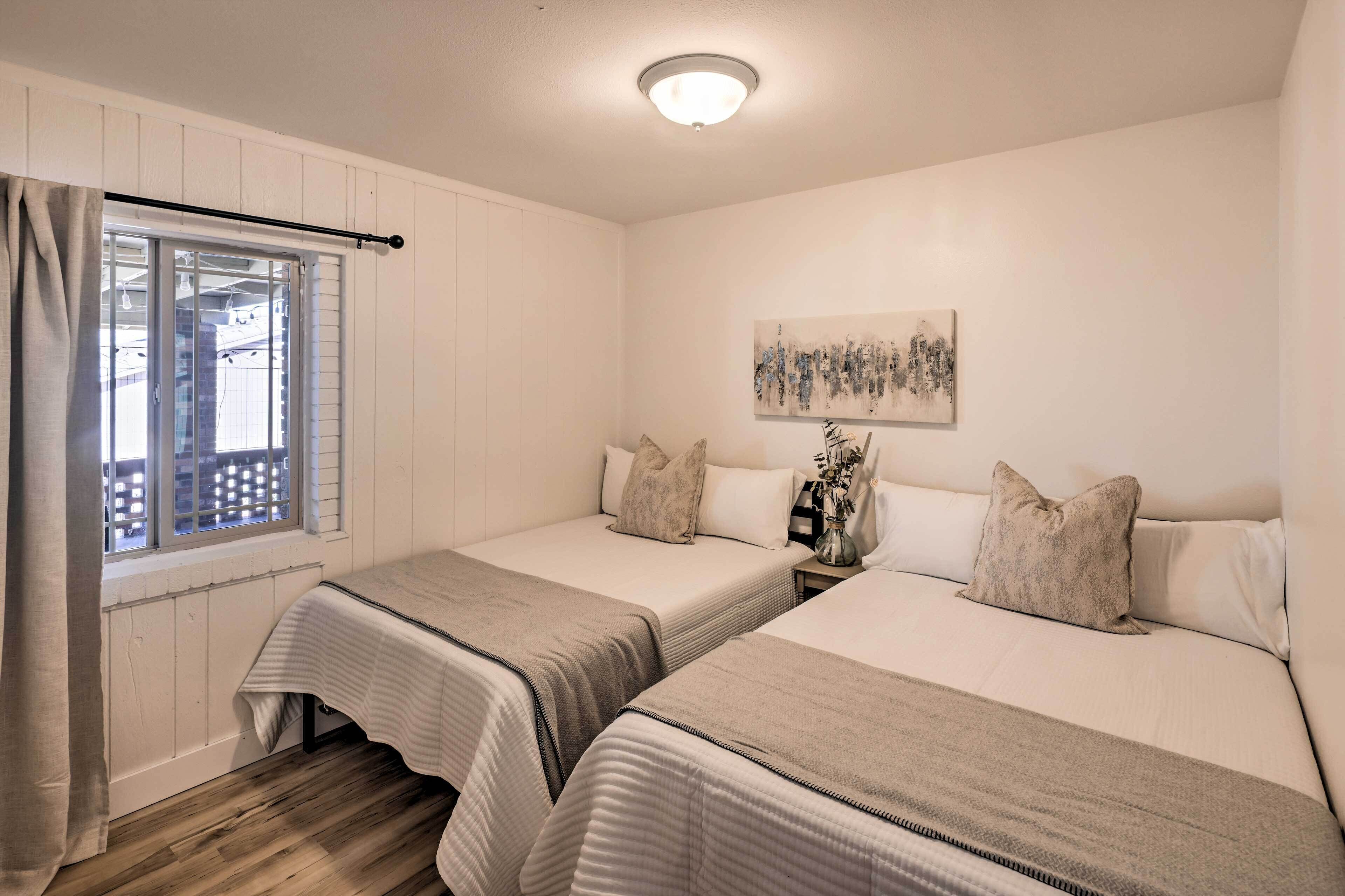 Un dormitorio con dos camas, una ventana con vistas, un cuadro en la pared y una lámpara en el techo.