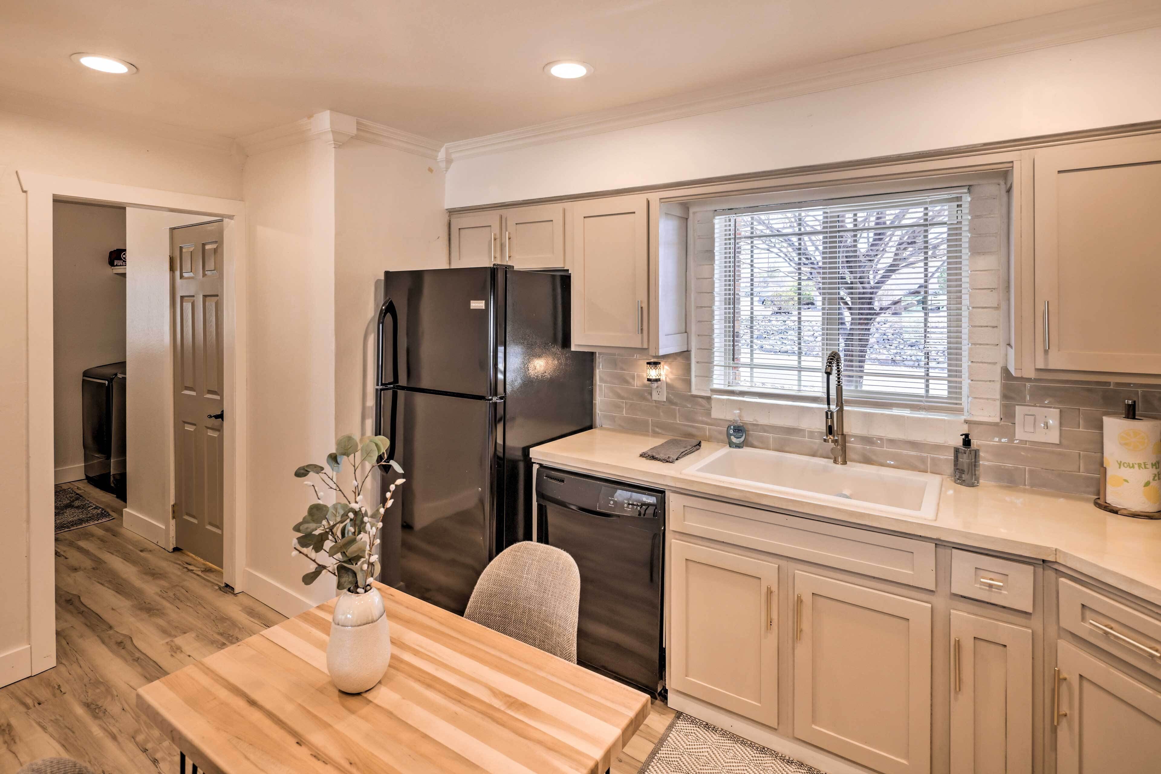 A modern kitchen with light-colored cabinets, a black refrigerator, and a dishwasher.