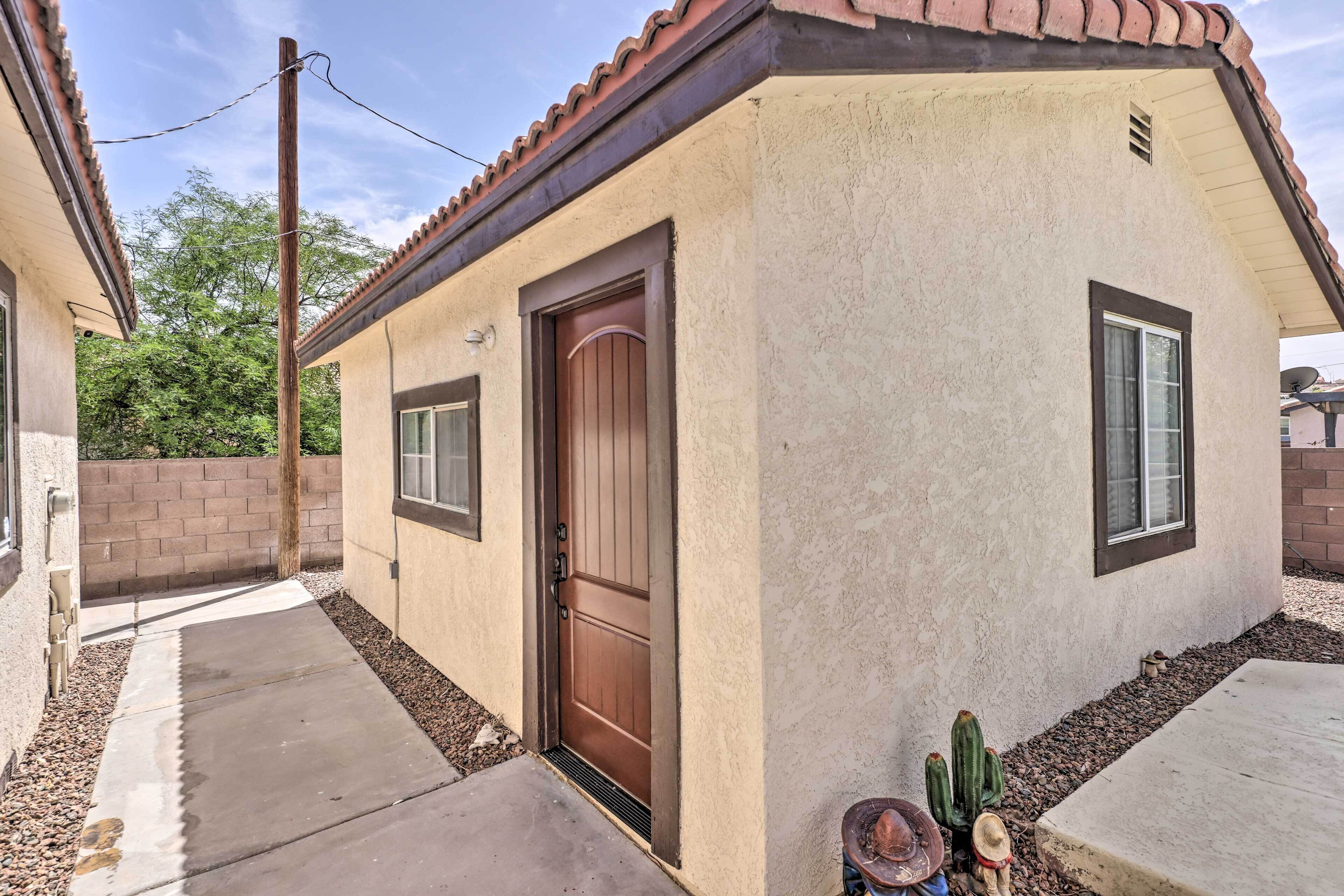 Une maison de plain-pied avec une porte marron, une fenêtre et un petit porche agrémenté d’un cactus et d’un chapeau.