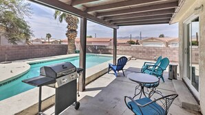 A covered patio with a pool, outdoor grill, and seating area.