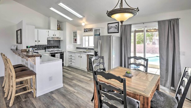 A modern kitchen with white cabinets, a central island, and a dining area with a wooden table and chairs.
