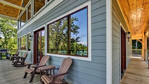 A wooden deck with Adirondack chairs and a view of trees.
