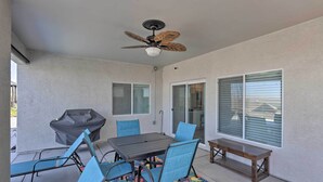 A covered patio with a table and chairs, a ceiling fan, and a bench.