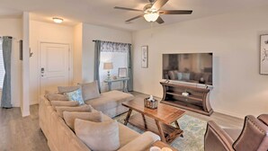 A living room with a sectional sofa, a coffee table, a TV stand, and a ceiling fan.