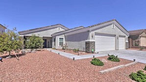 A two-story house with a garage, a stone accent wall, and a landscaped driveway with rocks and shrubs.