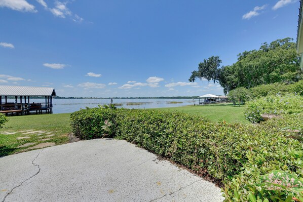A lakeside park with a gazebo, a covered picnic area, and a concrete path.