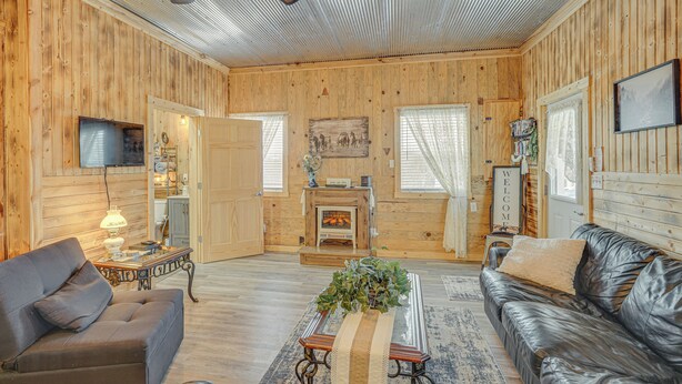 A log cabin interior with a fireplace, wooden walls, a leather sofa, a television, and a ceiling fan. - 'grace Place' Clark House on Farm: Shared Hot Tub! (Clark)