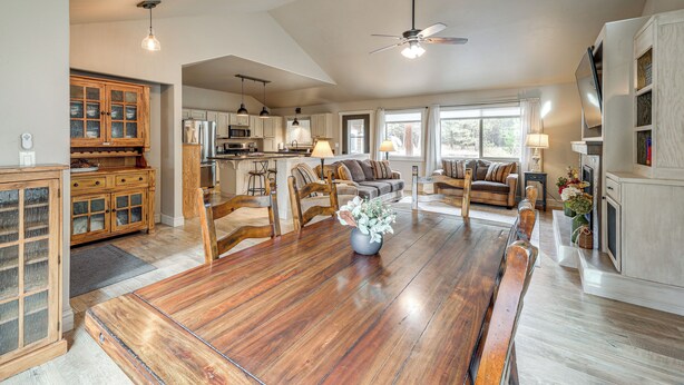 A spacious kitchen with wooden cabinets, a dining area with a large wooden table, and a living room with a sofa and chairs. - Kalispell Main House < 15 Mi to Flathead Lake (Kalispell)