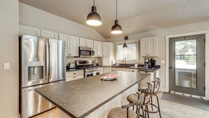 A modern kitchen with stainless steel appliances, a granite countertop, and bar stools. - Kalispell Main House < 15 Mi to Flathead Lake (Kalispell)