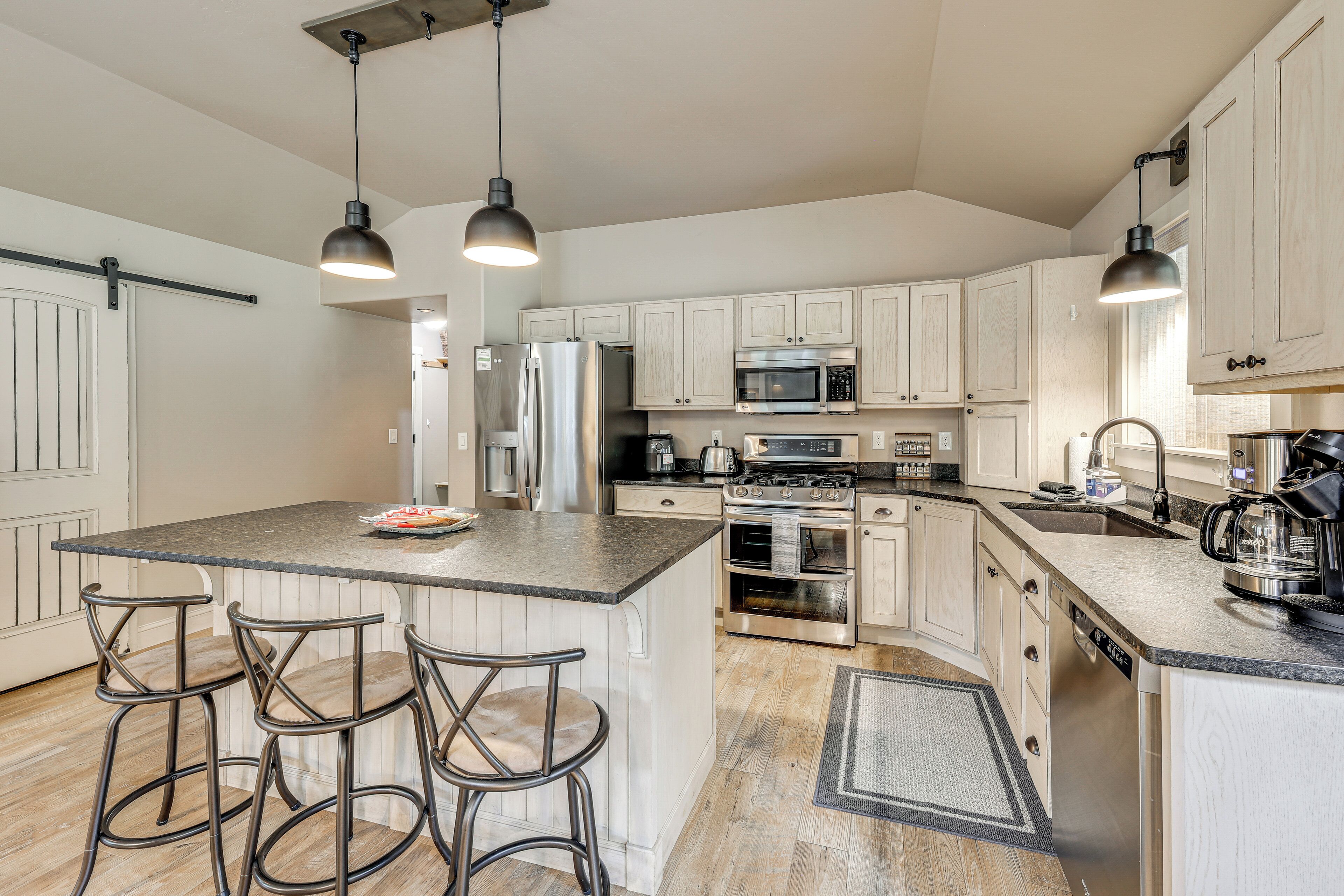 A spacious kitchen with white cabinetry, stainless steel appliances, and a central island with bar stools.