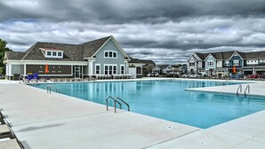 A large swimming pool with a covered area, adjacent to a row of houses with a similar architectural style.